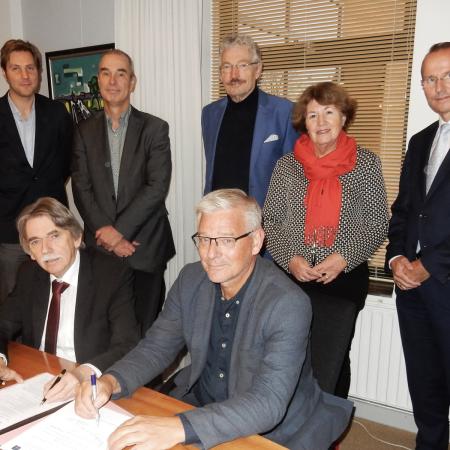 Burgemeester Gerard Beukema (links) en Jan Koolhof, voorzitter Stichting DelfSail 2021 tekenen de uitvoeringsovereenkomst. Staand v.l.n.r.: Arjen Luinenburg, gemeente Delfzijl, de wethouders Hans Ronde en Jan Menninga, Jeannette Blijdorp (directeur DelfSail 2021) en Johan Smit (penningmeester DelfSail 2021).